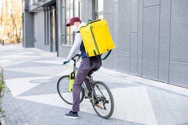 Eve servis için sarı termo çantalı bir teslimatçı. Eve yakın bir yerde. Kopyalamak için boş bir yer var.