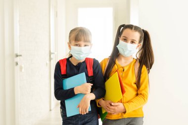Sırt çantalı koruyucu maskeli iki öğrenci arkadaş. Okul konseptinde gün