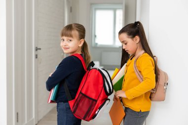 Konuşan ve sırlarını paylaşan iki küçük kız öğrenci. Eğitim, moda, arkadaşlık kavramı.