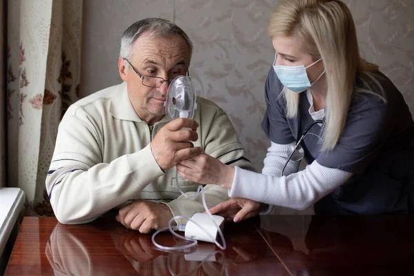 Porträt eines älteren Mannes, der zu Hause Grippe inhaliert. Der ältere Mann aus dem Kaukasus inhaliert zu Hause gegen Coronavirus mit einer Vernebelungsmaske. Gesundheitskonzept — Stockfoto