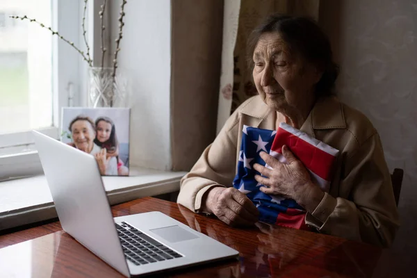 Independence Day celebration after quarantine. Granny looking at laptop screen and celebrating national holiday with her family online, care about senior people, personal technology, focus on woman — Stock Photo, Image