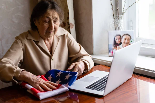 Дуже стара старша жінка з ноутбуком і прапором США — стокове фото
