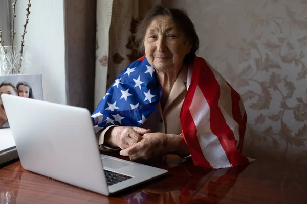 Independence Day celebration after quarantine. Granny looking at laptop screen and celebrating national holiday with her family online, care about senior people, personal technology, focus on woman — Stock Photo, Image