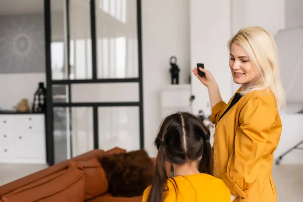 Sorrindo mãe e filha relaxante, operando ar condicionado com controle remoto, descansar em casa, desfrutar de ar fresco — Fotografia de Stock