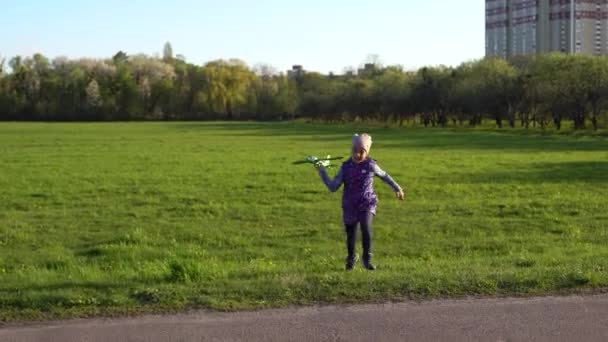 Menina com avião de brinquedo em mãos ao ar livre, parafuso vara de vento do motor de borracha — Vídeo de Stock