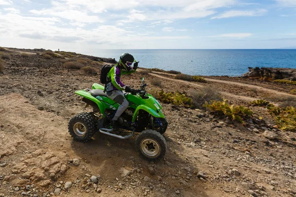 A young guy in sunglasses is riding an ATV on the beach — Stock Photo, Image