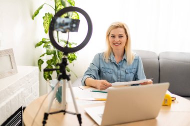 Sakin akıllı kadın yatak odasında kameranın önünde duruyor ve elinde bir rulo kağıt var.