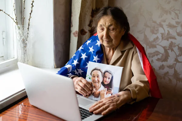 Independence Day celebration after quarantine. Granny looking at laptop screen and celebrating national holiday with her family online, care about senior people, personal technology, focus on woman — Stock Photo, Image