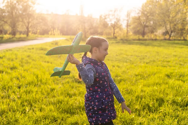 Menina com avião de brinquedo em mãos ao ar livre, parafuso vara de vento do motor de borracha — Fotografia de Stock