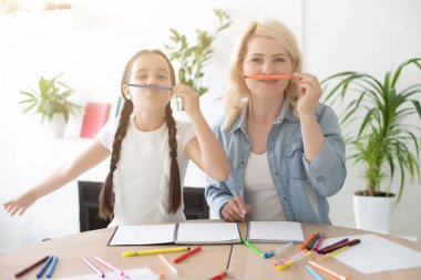 Anne ve kız birlikte ev ödevi yapıyorlar.