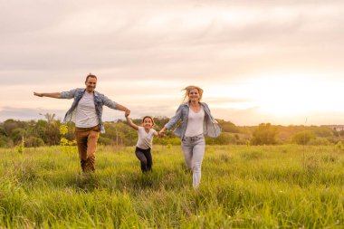 Mutlu aile: anne baba ve kız gün batımında doğada