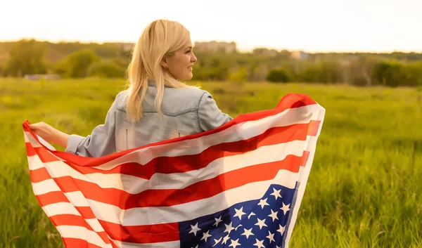 Pays, patriotisme, fête de l'indépendance et concept des gens - heureuse jeune femme souriante avec drapeau national américain sur le terrain — Photo