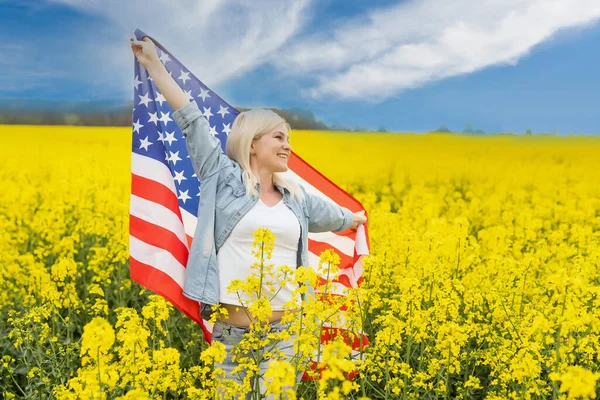 Land, patriotism, självständighetsdag och människor koncept - glad leende ung kvinna med nationell amerikansk flagga på fältet — Stockfoto