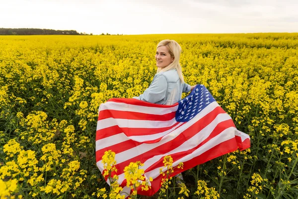 Land, patriotism, självständighetsdag och människor koncept - glad leende ung kvinna med nationell amerikansk flagga på fältet — Stockfoto