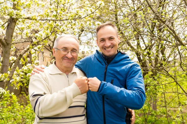 Vater und Sohn blicken im Garten in die Kamera — Stockfoto