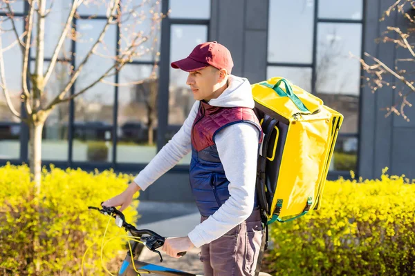 Liefermann steht mit gelbem Thermo-Rucksack für Essensausgabe in der Nähe des Hauseingangs mit leerem Platz zum Kopieren von Kleister — Stockfoto