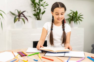 Evdeki masaüstünde çalışma ortamı. Laptop, yazı malzemeleri, kitaplar, defter masanın üstünde. Mesafe öğrenmeye hazırlanıyorum. Okula dönelim. Serbest İşçi, merkez ofis..