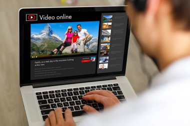 Adam gelecek seyahati planlamak için bilgi topluyor, web sitesinde internet üzerinden rezervasyon yaptırıyor, internetten bir geziyle ilgili video seyrediyor.