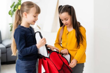 Konuşan ve sırlarını paylaşan iki küçük kız öğrenci. Eğitim, moda, arkadaşlık kavramı.