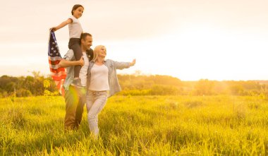 Buğday tarlasında mutlu bir aile ve arkasında Amerikan bayrağı var..