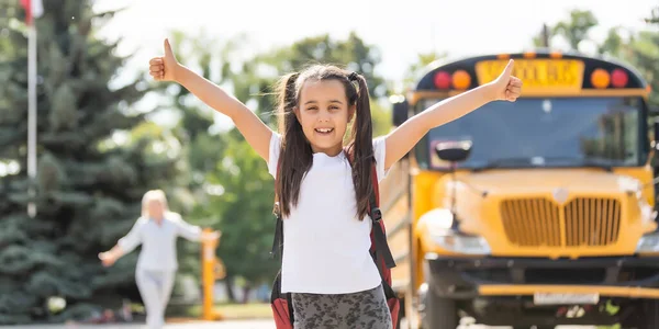 Kinderen student loopt in moeders handen om haar te knuffelen na terug naar school in de buurt van de schoolbus — Stockfoto