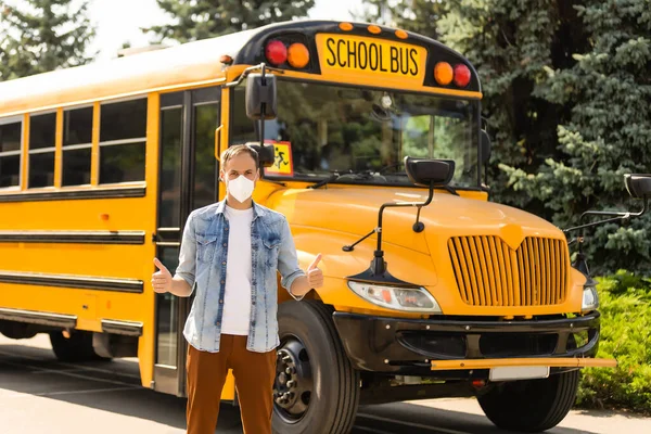 masked teacher near the school bus