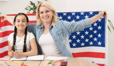 Vatansever bayram. Mutlu aile, anne ve kızı evde Amerikan bayrağı taşıyan kız çocuğu. ABD 4 Temmuz 'u kutladı.