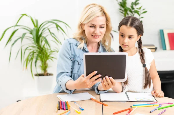 Terug naar school. Gelukkig kind en volwassene zitten aan het bureau. Meisje doet huiswerk of online onderwijs. — Stockfoto