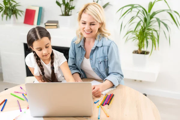 아름다운 젊은 여성 과 그 의귀여운 딸은 집에서 노트북을 사용하고 있습니다. 함께 시간을 보내는 일을 즐긴다. — 스톡 사진
