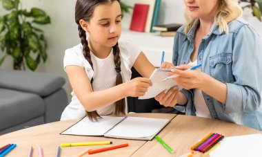 Anne ve kız güzel ve mutlu anneler günü için kağıt ve kalemlerle birlikte masaya oturarak bir kart yapın.