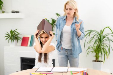 Anne, kızına ev ödevinde yardım ediyor.