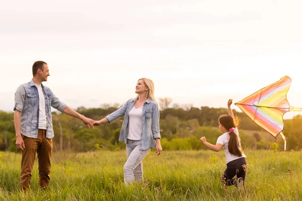 Szczęśliwa rodzina w świetle wieczoru w parku. Światła słońca. Mama, tata i dziecko szczęśliwego spaceru o zachodzie słońca. Koncepcja szczęśliwej rodziny — Zdjęcie stockowe