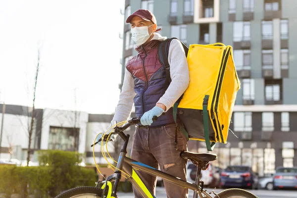 Liefermann steht mit gelbem Thermo-Rucksack für Essensausgabe in der Nähe des Hauseingangs mit leerem Platz zum Kopieren von Kleister — Stockfoto