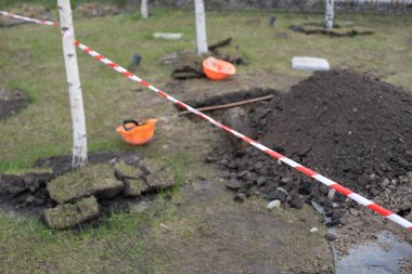 Çimlere kazılmış bir çukurun kenarında dinlenen tahta kürek.