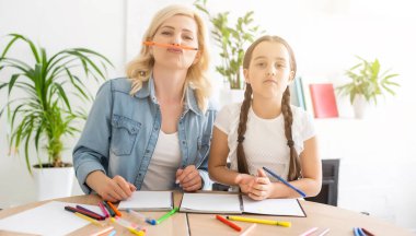 Başında anne sembolleriyle evde eğitim gören küçük bir kız.