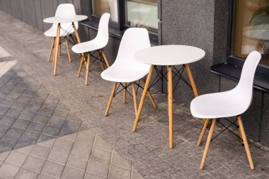 Açık masa ve kafenin duvarına yakın iki sandalye.,