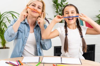 Güzel liseli kız annesiyle evde ödev yapıyor.