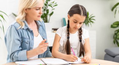 Anne, kızına ev ödevinde yardım ediyor.
