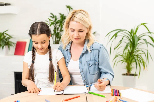 Anne ve kızı evde resim çizerek vakit geçiriyorlar.
