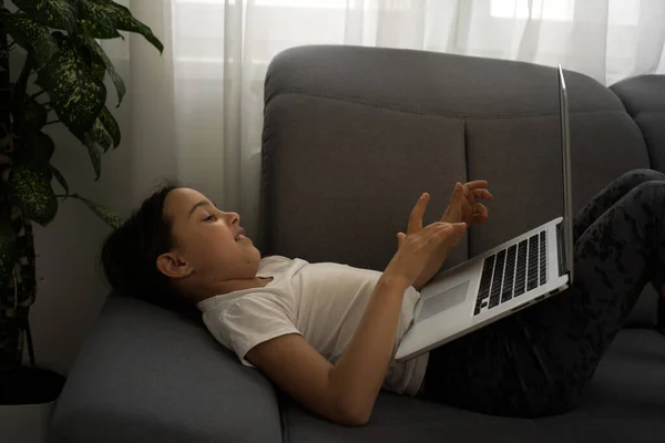 Verveeld klein meisje met laptop thuis. Leuk kind dat huiswerk maakt op de computer. Modern online onderwijs, communicatie en technologie concept, kopieerruimte. — Stockfoto