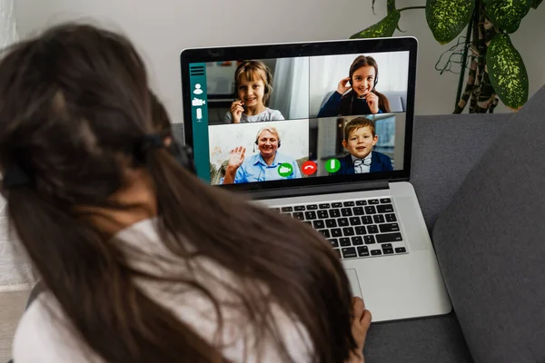 Mesafe öğrenme. Kulaklıklı neşeli küçük kız bilgisayarını kullanarak internetten e-öğrenim sistemini inceliyor..