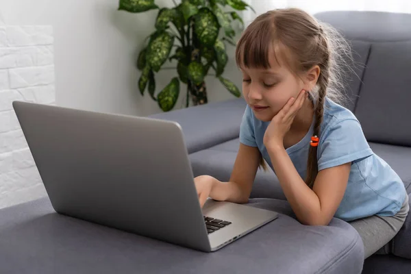 Holčička studuje s počítačem, holčička s notebookem online. — Stock fotografie