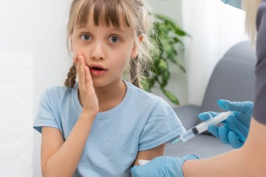 Küçük kız muayenehanedeki çocuk doktorundan aşı oluyor.