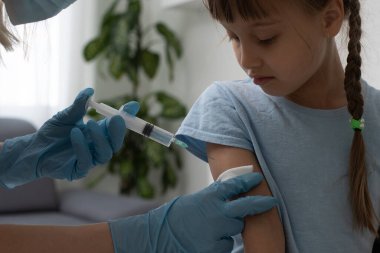 Hemşire küçük kız hastaya aşı yapıyor.