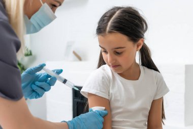 Küçük kız muayenehanedeki çocuk doktorundan aşı oluyor.