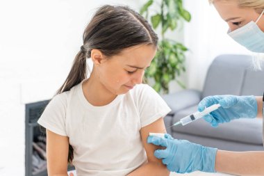 Küçük kız muayenehanedeki çocuk doktorundan aşı oluyor.