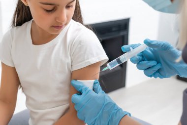 Hemşire küçük kız hastaya aşı yapıyor.