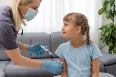 Küçük kız muayenehanedeki çocuk doktorundan aşı oluyor.