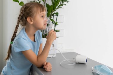 Küçük kız evde nebulizörle solunum yapıyor. çocuk astım spreyi soluması buhar buharı, öksürük konsepti..