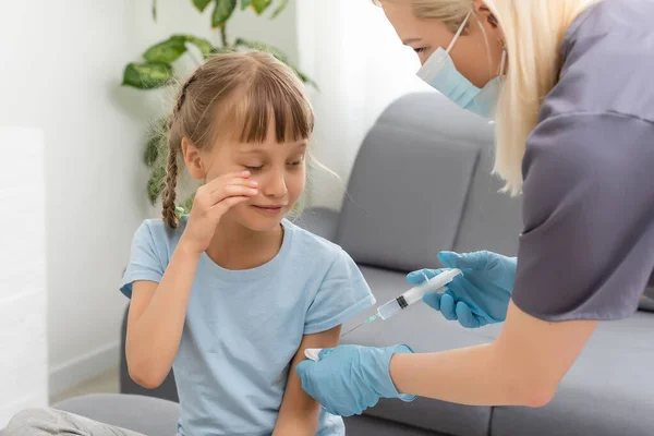 Een klein meisje met tranen in haar ogen is erg bang voor vaccinatie. De baby huilt terwijl hij zijn ogen sluit van de pijn. Portret van een snikkend kind dat in de schouder wordt geïnjecteerd. Medisch concept voor kinderen, — Stockfoto